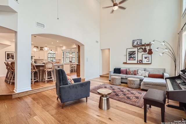 living room with a towering ceiling and light wood-type flooring