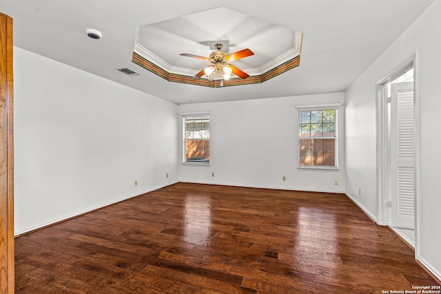 unfurnished bedroom with ceiling fan, ornamental molding, a raised ceiling, and dark hardwood / wood-style flooring