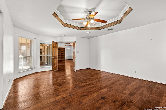 unfurnished room with dark wood-type flooring, a raised ceiling, crown molding, and ceiling fan