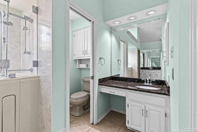 bathroom with tiled shower, tile patterned floors, vanity, and toilet