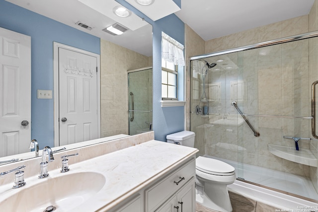 bathroom with vanity, a shower with shower door, toilet, and tile patterned floors