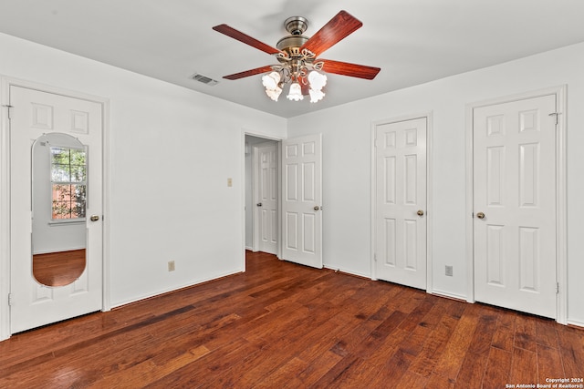 unfurnished bedroom featuring ceiling fan, two closets, and dark hardwood / wood-style flooring