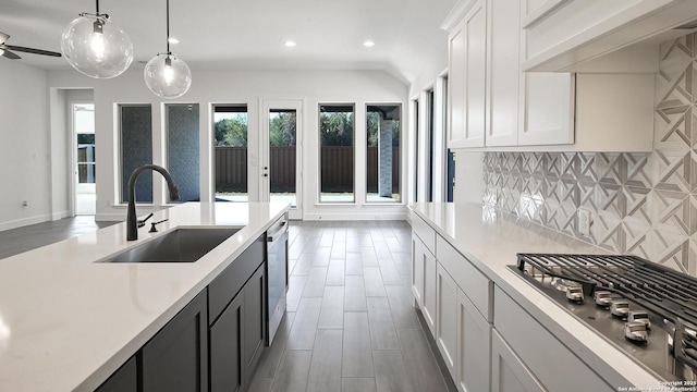 kitchen featuring white cabinetry, stainless steel appliances, backsplash, hanging light fixtures, and sink