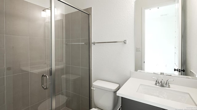 bathroom with an enclosed shower, vanity, and toilet