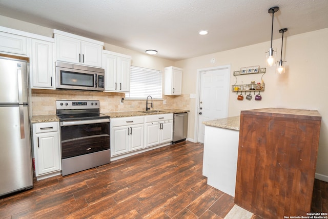 kitchen with pendant lighting, sink, dark hardwood / wood-style floors, white cabinets, and appliances with stainless steel finishes