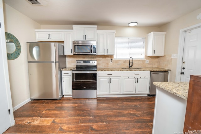 kitchen featuring light stone counters, decorative backsplash, stainless steel appliances, sink, and dark hardwood / wood-style flooring