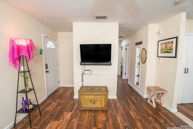 foyer entrance with a textured ceiling and dark wood-type flooring