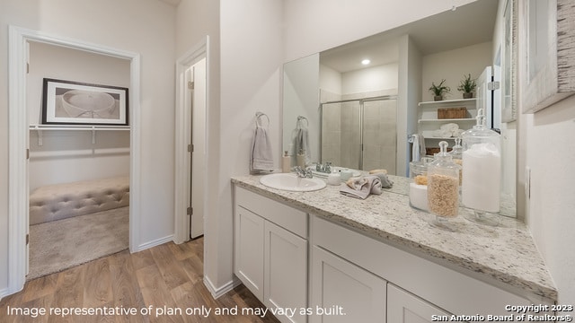 full bath with vanity, baseboards, a shower stall, and wood finished floors