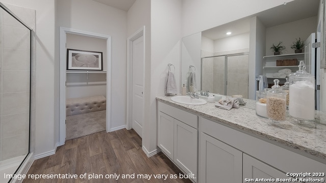 full bathroom featuring vanity, baseboards, a stall shower, and wood finished floors