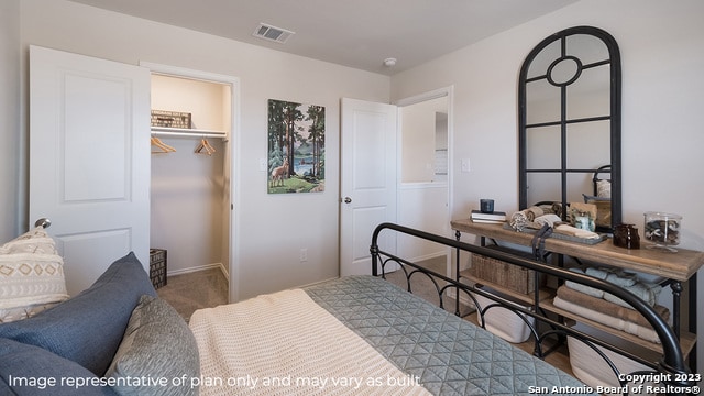 carpeted bedroom with a spacious closet, baseboards, a closet, and visible vents