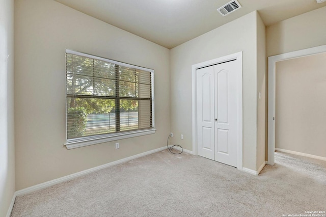 unfurnished bedroom with light carpet and a closet