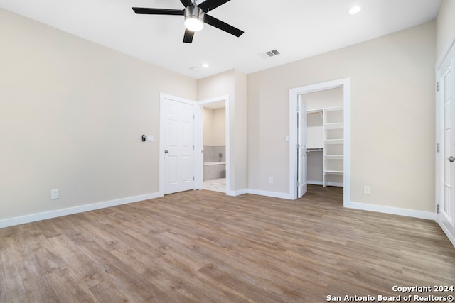 unfurnished bedroom featuring a closet, ceiling fan, light hardwood / wood-style flooring, and a walk in closet