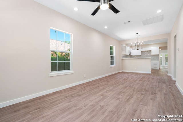 unfurnished living room featuring light hardwood / wood-style floors and ceiling fan with notable chandelier