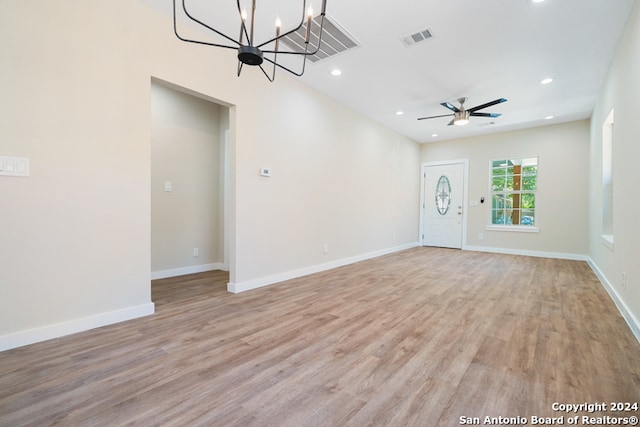 unfurnished living room with light hardwood / wood-style flooring and ceiling fan with notable chandelier