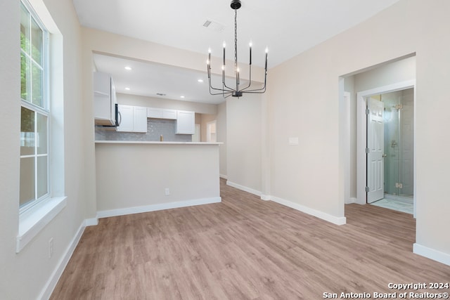 unfurnished dining area featuring light hardwood / wood-style flooring and a chandelier