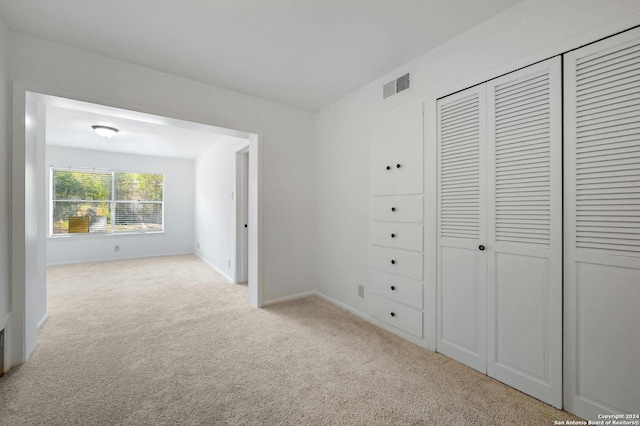 unfurnished bedroom with a closet and light colored carpet