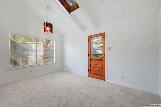 empty room featuring a skylight, beam ceiling, carpet flooring, and high vaulted ceiling