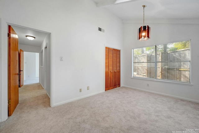 carpeted spare room with high vaulted ceiling