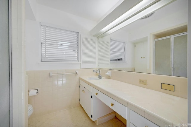 bathroom featuring vanity, tile walls, tile patterned flooring, a shower with shower door, and toilet