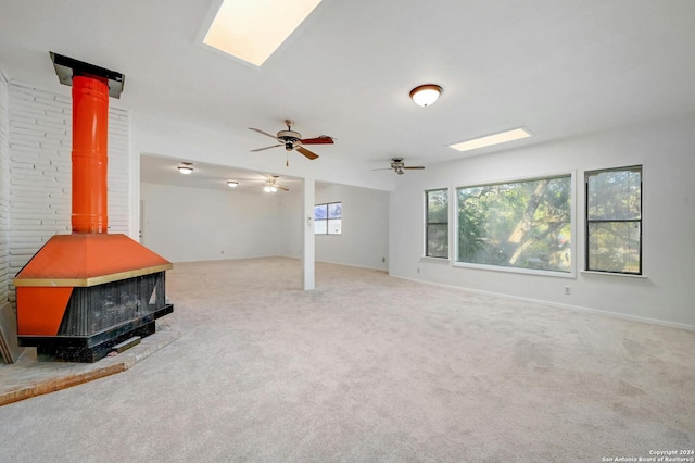 basement with carpet floors, a wood stove, and ceiling fan