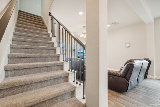 stairway with ceiling fan and hardwood / wood-style flooring