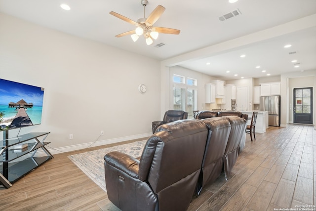 living room with a healthy amount of sunlight, ceiling fan, and light hardwood / wood-style flooring