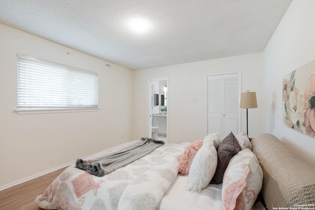 bedroom featuring ensuite bathroom, hardwood / wood-style flooring, a closet, and a textured ceiling