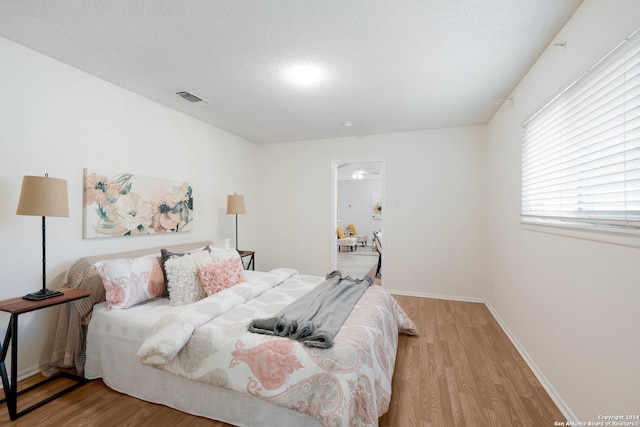 bedroom featuring a textured ceiling and light hardwood / wood-style flooring