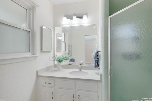 bathroom featuring vanity and a shower with door