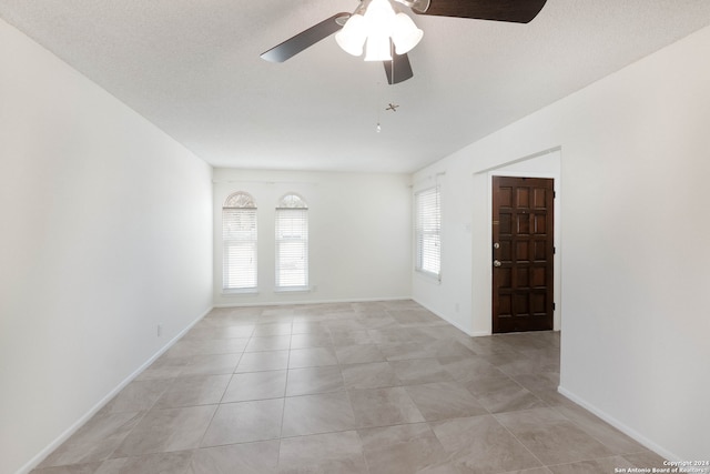 spare room with ceiling fan, light tile patterned flooring, and a textured ceiling