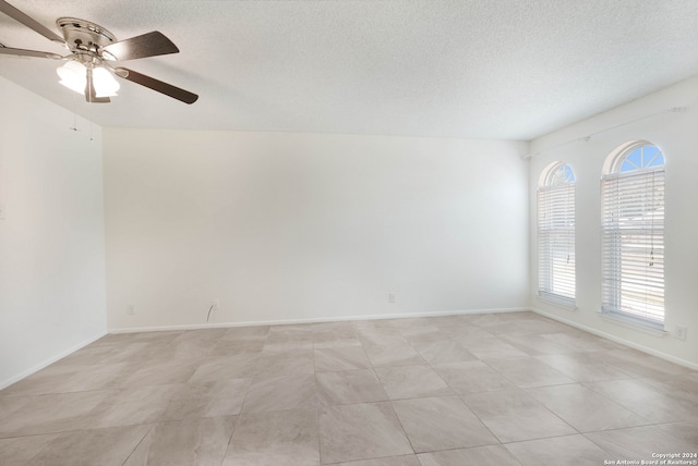 spare room featuring ceiling fan, a textured ceiling, and light tile patterned floors