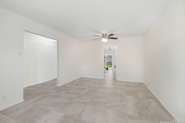 empty room with ceiling fan and a textured ceiling