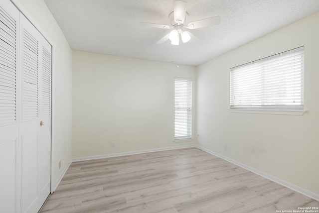 unfurnished bedroom with ceiling fan, a textured ceiling, light hardwood / wood-style flooring, and a closet