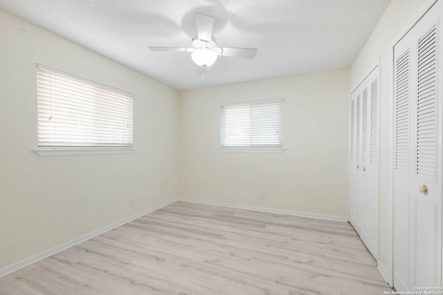 unfurnished bedroom with ceiling fan, a textured ceiling, and light wood-type flooring