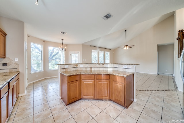 kitchen with light stone counters, pendant lighting, light tile patterned floors, and a kitchen island