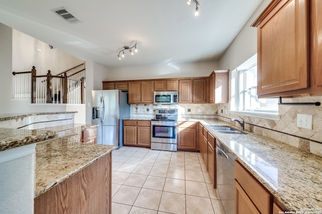 kitchen with stainless steel appliances, tasteful backsplash, light stone counters, and sink