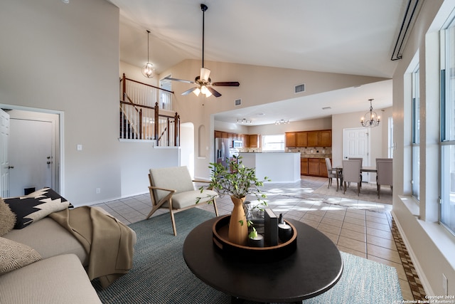 tiled living room featuring ceiling fan with notable chandelier and high vaulted ceiling