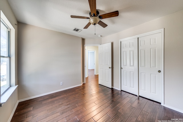 unfurnished bedroom featuring ceiling fan, a closet, dark hardwood / wood-style flooring, and multiple windows