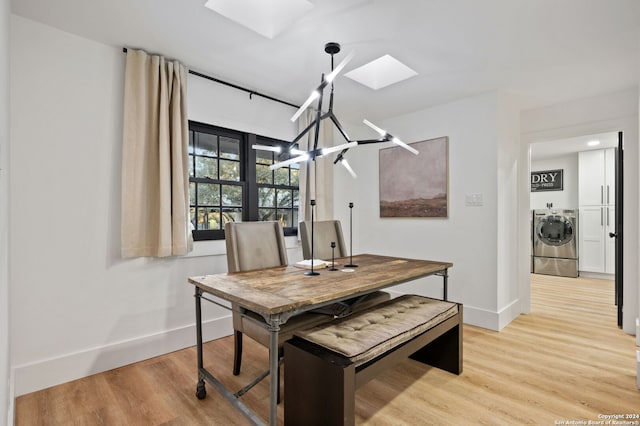 dining space featuring a notable chandelier, washing machine and clothes dryer, a skylight, and light hardwood / wood-style flooring