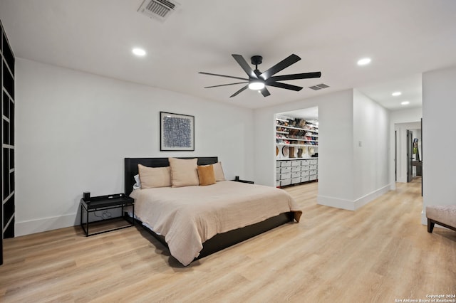 bedroom featuring light wood-type flooring, ceiling fan, a closet, and a walk in closet