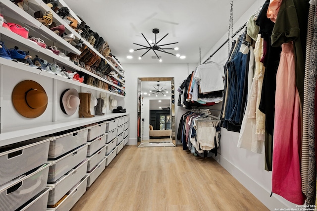 walk in closet featuring an inviting chandelier and light hardwood / wood-style floors