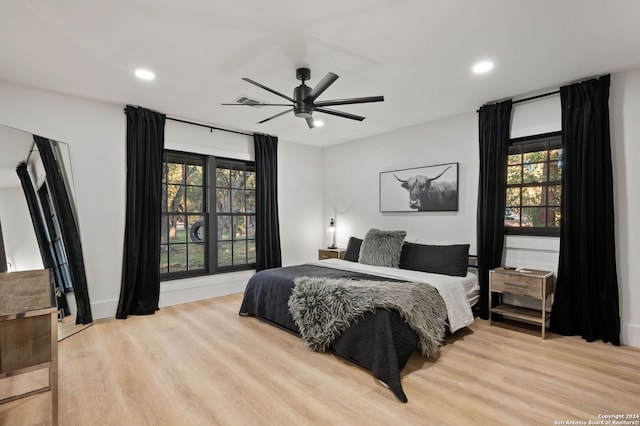 bedroom with light wood-type flooring, multiple windows, and ceiling fan