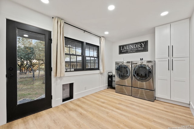 clothes washing area with washing machine and clothes dryer, light hardwood / wood-style floors, and cabinets