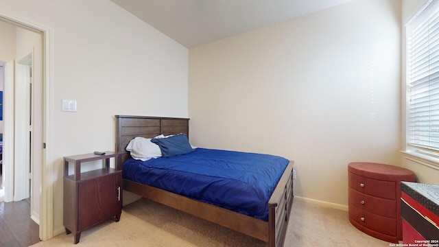 bedroom with light colored carpet and lofted ceiling