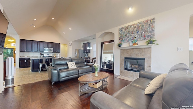 living room featuring light wood-type flooring, a fireplace, and high vaulted ceiling