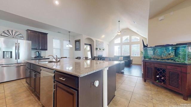 kitchen featuring pendant lighting, lofted ceiling, sink, a kitchen island with sink, and appliances with stainless steel finishes