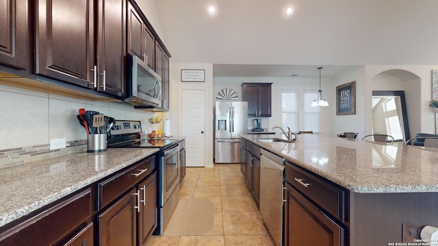 kitchen with pendant lighting, sink, an island with sink, appliances with stainless steel finishes, and light tile patterned floors