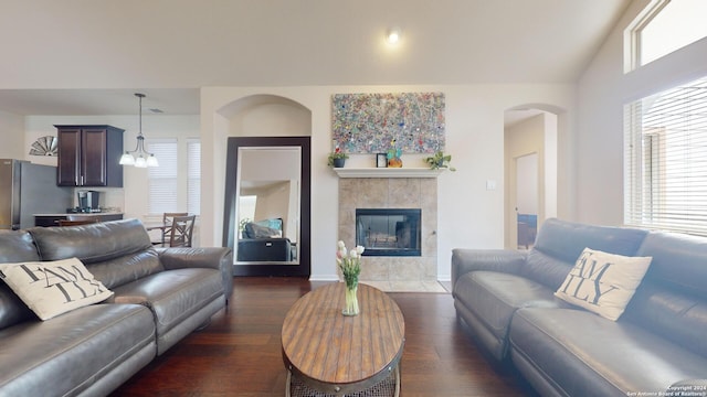 living room featuring a notable chandelier, lofted ceiling, dark hardwood / wood-style floors, and a tile fireplace