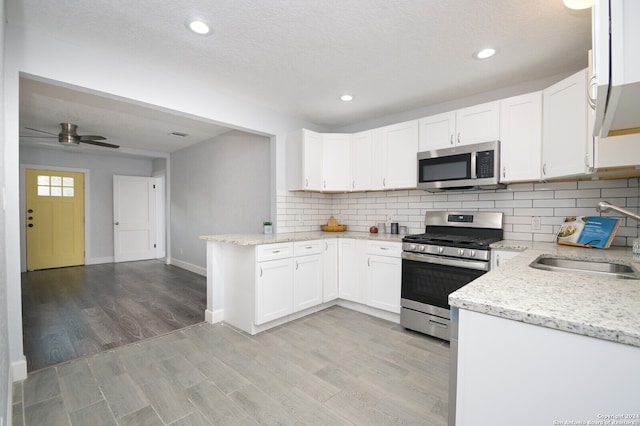 kitchen with light hardwood / wood-style floors, ceiling fan, sink, white cabinets, and appliances with stainless steel finishes