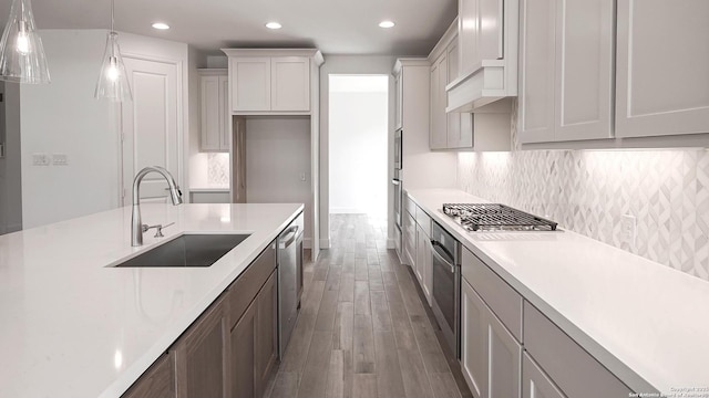 kitchen with appliances with stainless steel finishes, light countertops, a sink, and tasteful backsplash